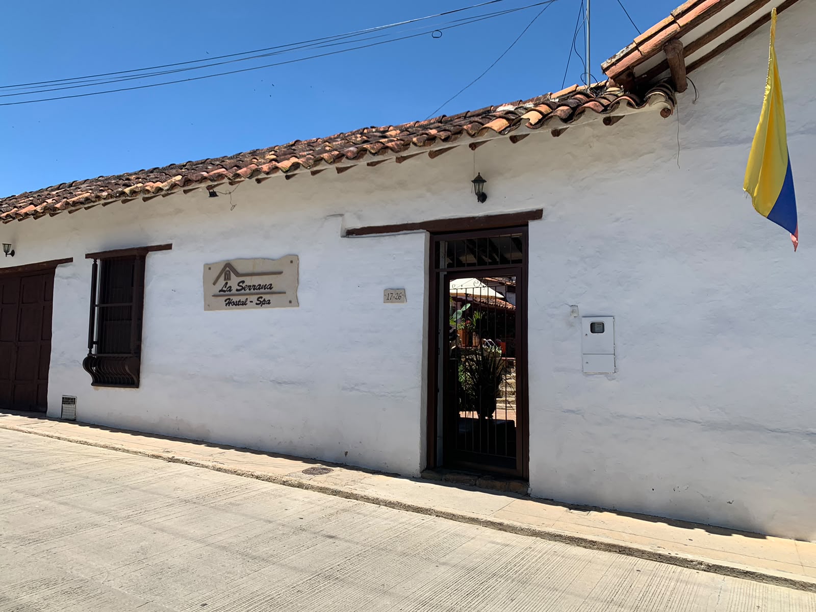 Fachada blanca encalada de La Serrana con tejado de barro y la bandera de Colombia.