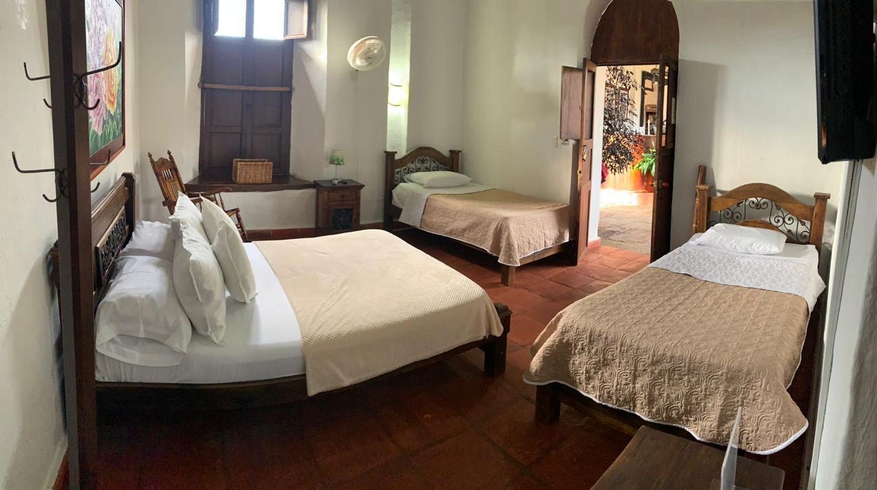 Habitación de acomodación múltiple con una cama doble y dos camas sencillas, y puerta al patio.