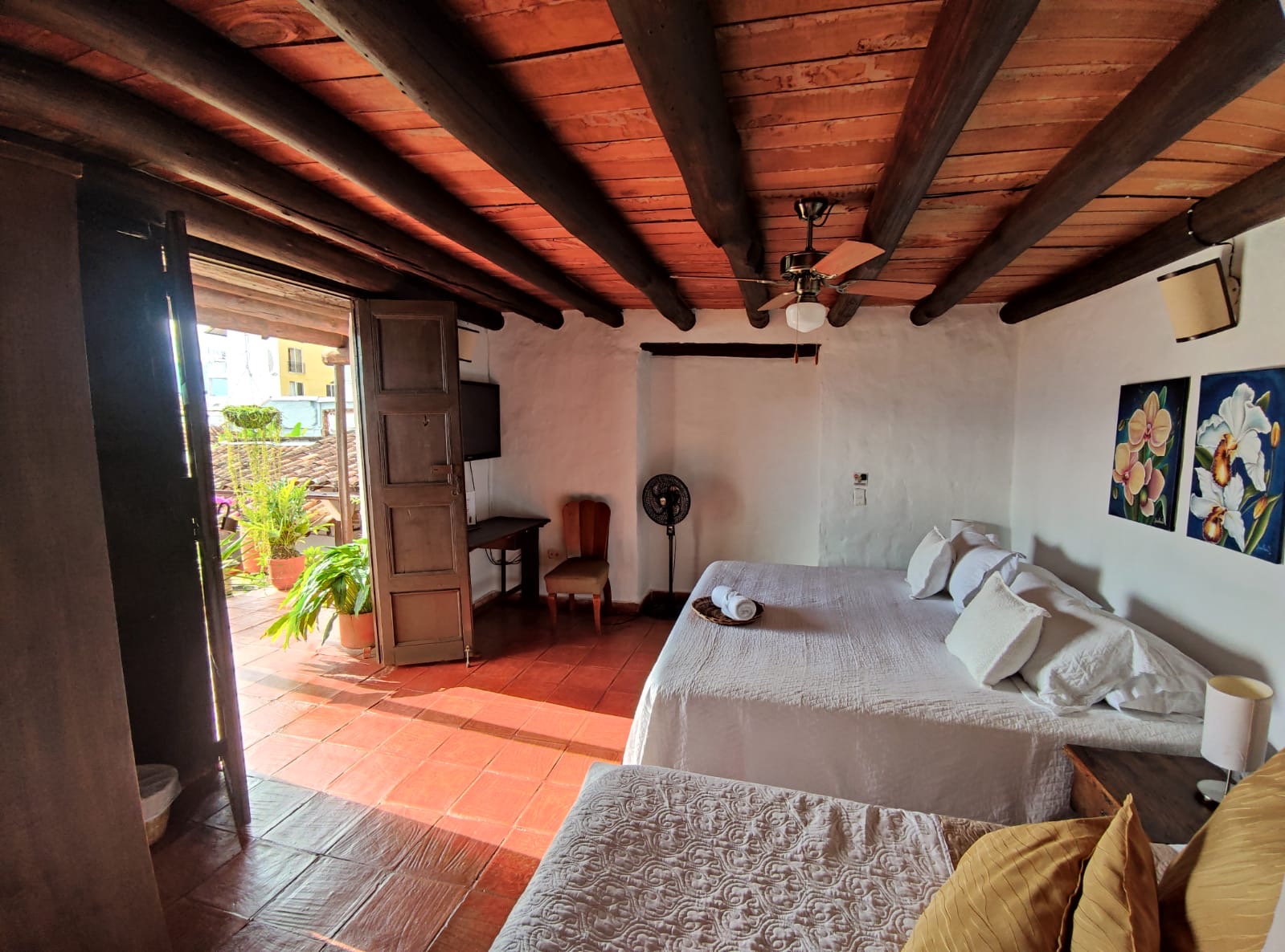 Habitación con puerta doble abierta a una terraza privada, con vista a los tejados de barro del pueblo.